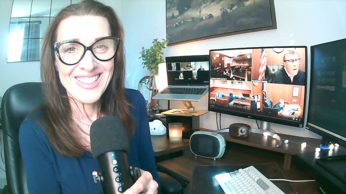 Julie at her desk, mic in hand, court on every screen